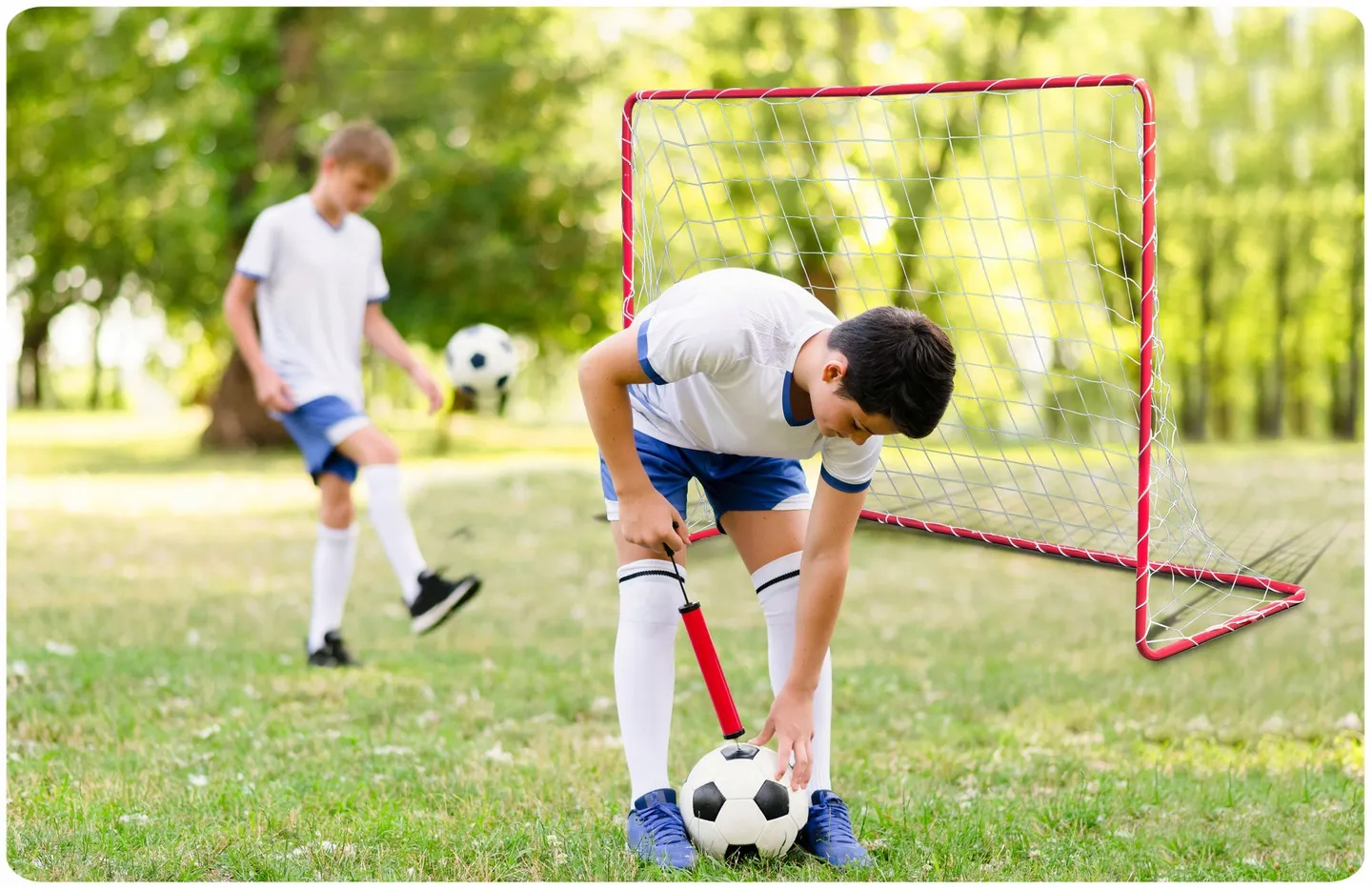 Bērni uz zāliena pie futbola vārtiem ar bumbas sagatavošanu sitienam