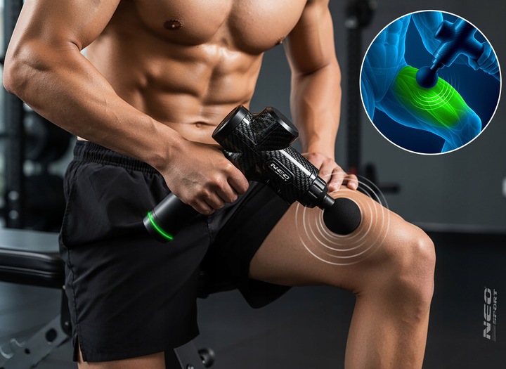 Vīrietis treniņu zālē masē augšstilbu ar Neo-Sport masāžas pistoli un anatomisku akcentu