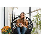 Piekarināms krēsls uz balkona ar cilvēku, kas sēž ar krūzi un džinsiem