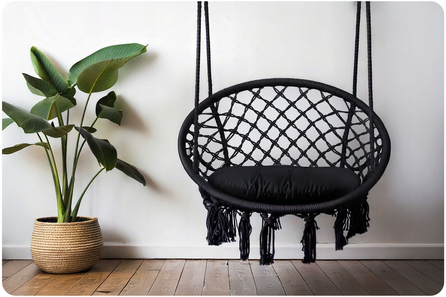 Piekarināms BOHO krēsls melnā krāsā pie sienas blakus lielam telpaugam, redzams sānskats