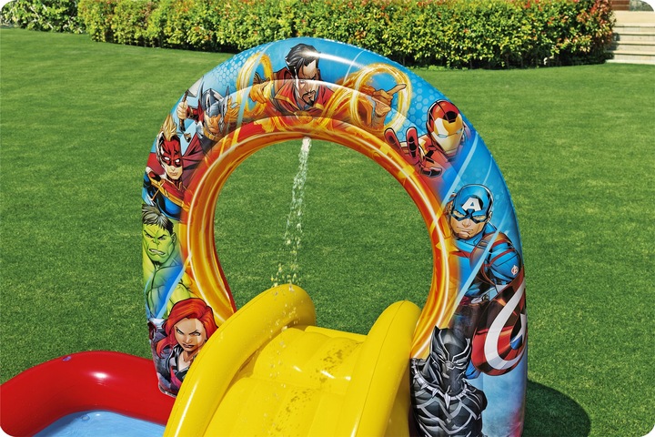 Tuvplānā redzams piepūšamais slidkalniņš un dekoratīvā Avengers arka