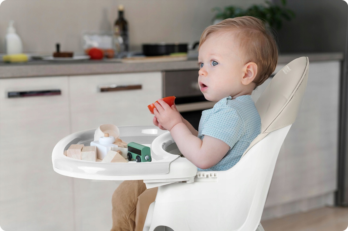 Bērns sēž Ricokids Milo barošanas krēsliņā pie paplātes virtuvē