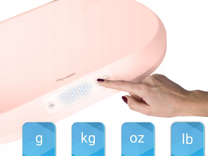 Rozā Nukido zīdaiņu svari tuvplānā ar roku, kas nospiež vadības pogu, un redzami vienību apzīmējumi g, kg, oz, lb