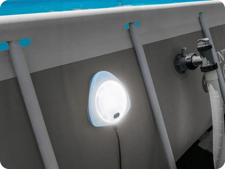 Iedegta baseina lampa piestiprināta pie baseina sienas blakus filtrācijas šļūtenei