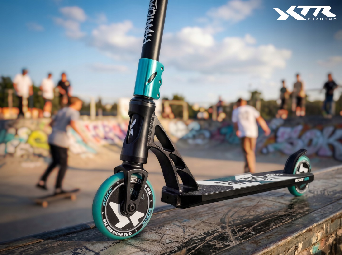 SOKE XTR Phantom triku skrejriteņa priekšējais mezgls un stūres kāts no tuvplāna, fonā redzams skateparks