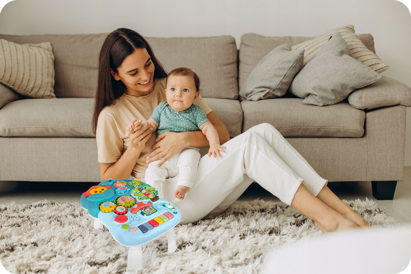Bērns ar pieaugušo sēž pie Ricokids izglītojošā galdiņa viesistabā uz paklāja