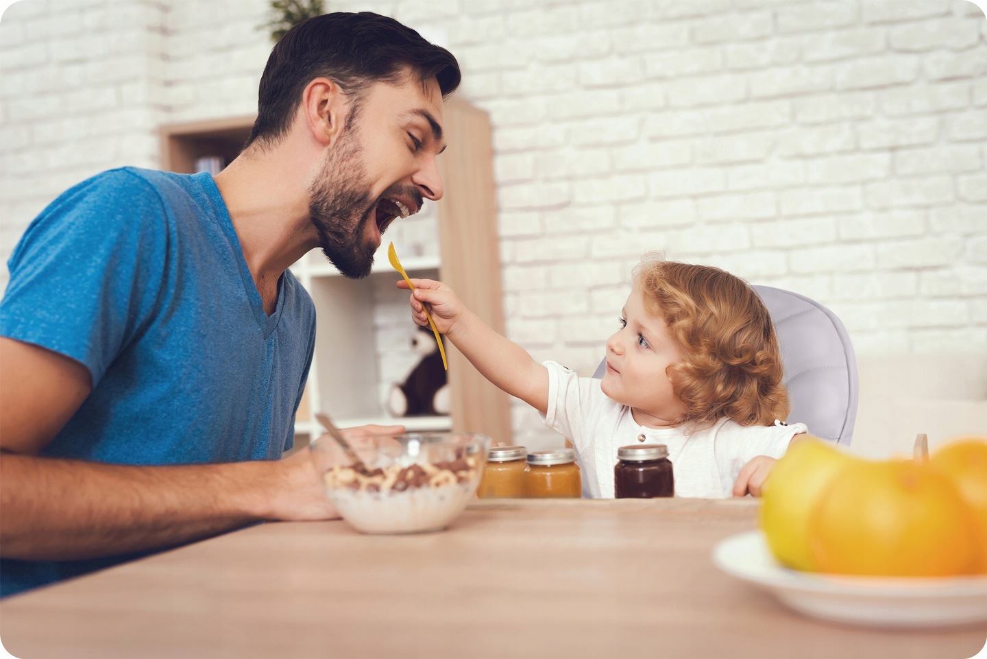 Ģimenes maltīte pie galda, bērns sēž Ricokids Tulo barošanas krēslā