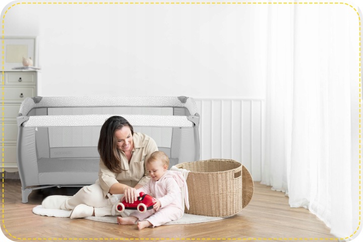Ricokids ceļojumu gultiņa bērnistabā, kur pie grīdas rotaļājas pieaugušais ar bērnu