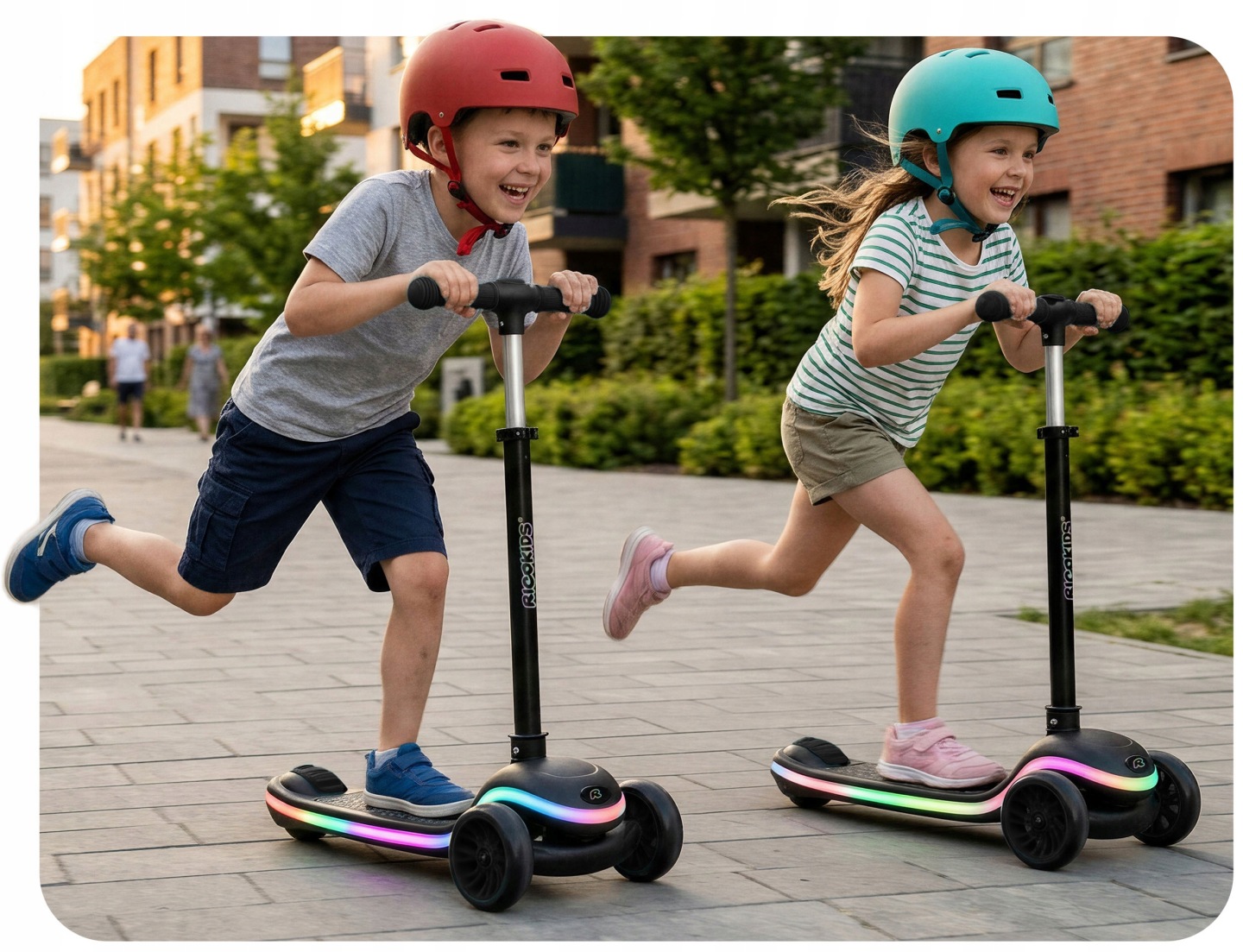 Divi bērni ar ķiverēm skrienot izmanto Ricokids Leddi trīsriteņu skrejriteņus pilsētas ielā