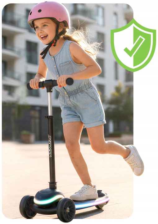 Bērns ar ķiveri brauc ar Ricokids Leddi skrejriteni pilsētas vidē, redzams drošas braukšanas akcents