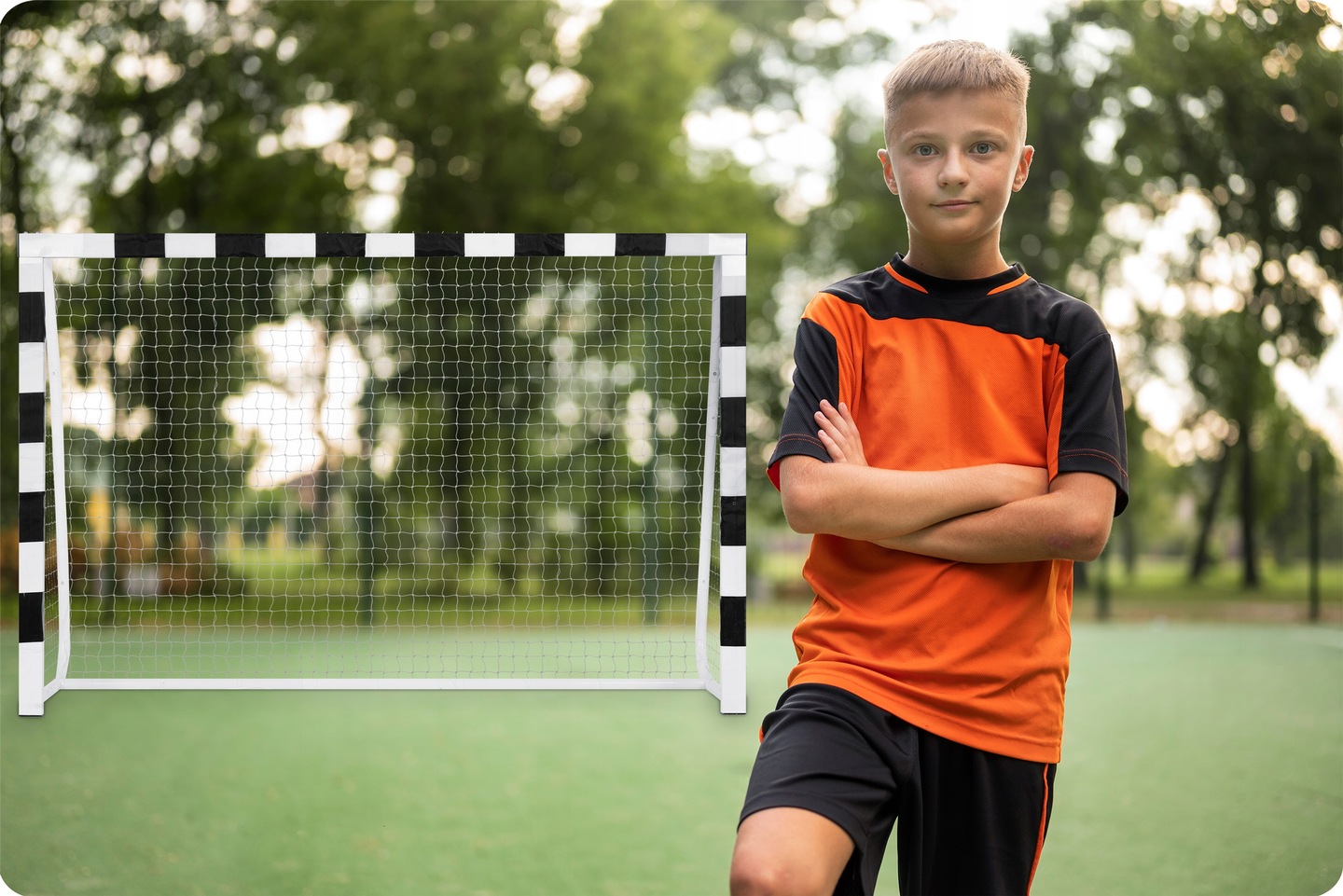 Futbola vārti stadionā blakus zēnam ar sakrustotām rokām