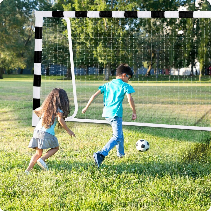 Futbola vārti parkā, kur bērni spēlē bumbu pie tīkla