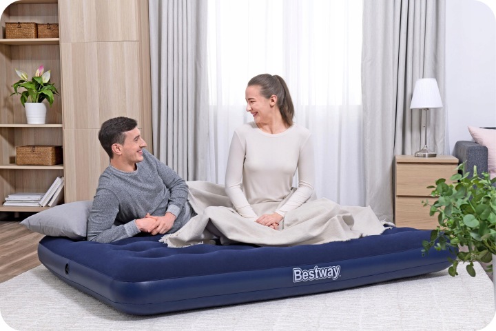 Pāris sēž uz Bestway 67287 matrača gaišā guļamistabā